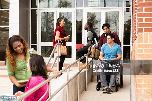 education: disabled student helped down wheelchair ramp. college campus. - rolstoelvriendelijk stockfoto's en -beelden