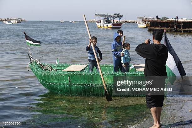 Palestinian children pose for a picture on a makeshift boat made of plastic bottles on April 18, 2015 at the port of Gaza City. AFP PHOTO / MOHAMMED...