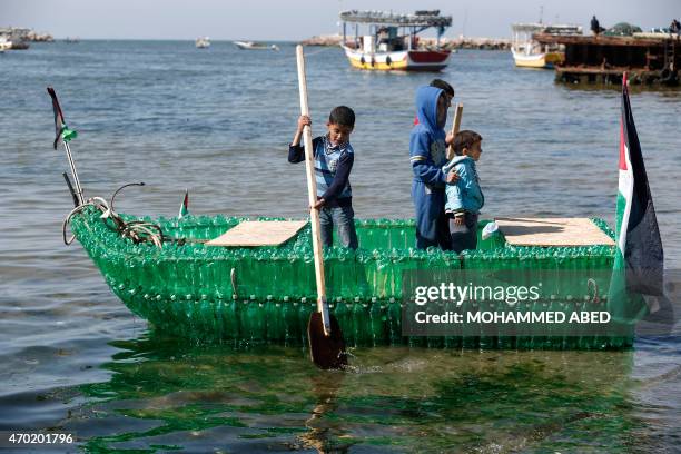 Palestinian children pose for a picture on a makeshift boat made of plastic bottles on April 18, 2015 at the port of Gaza City. AFP PHOTO / MOHAMMED...