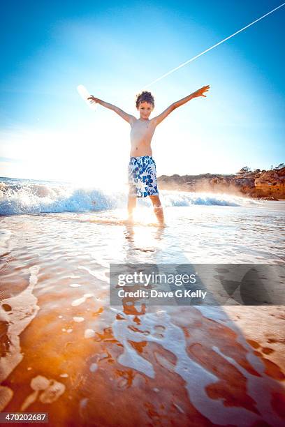 boy standing on a beach - com os pés na água imagens e fotografias de stock