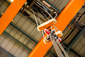 Close-up of an orange crane pulley over an orange ceiling
