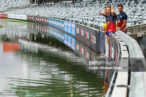 Bulldogs players Luke Dahlhaus Lachie Hunter and Koby Stevens look at the ground that is under water after a storm passed through before the round...