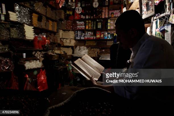 Vendor uses a lantern to read inside his shop at a market in the capital Sanaa on April 18, 2015 on the sixth day of a power outage across the...