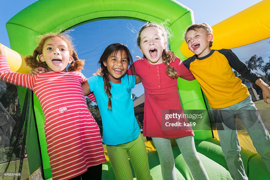 Four multi-ethnic children playing on bouncy castle