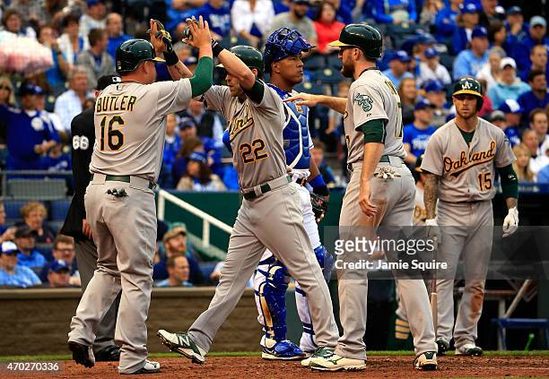 Josh Reddick of the Oakland Athletics is congratulated by Billy Butler and Ike Davis after hitting a home run during the 4th inning of the game...