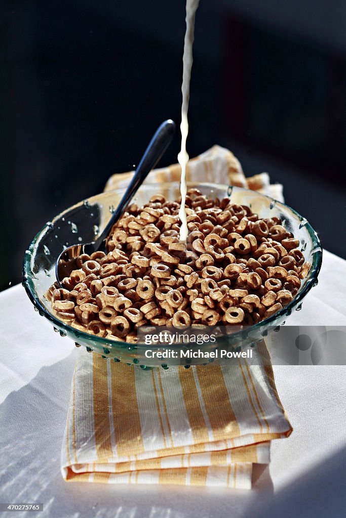 Whole grain breakfast cereal with milk pouring.