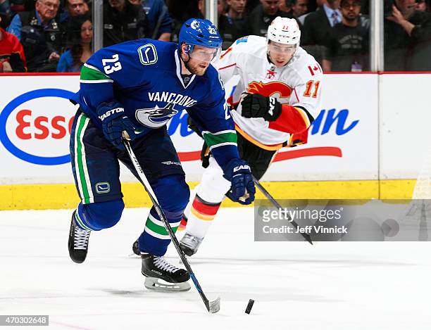 Mikael Backlund of the Calgary Flames looks on as Alexander Edler of the Vancouver Canucks skates up ice with the puck during Game Two of the Western...