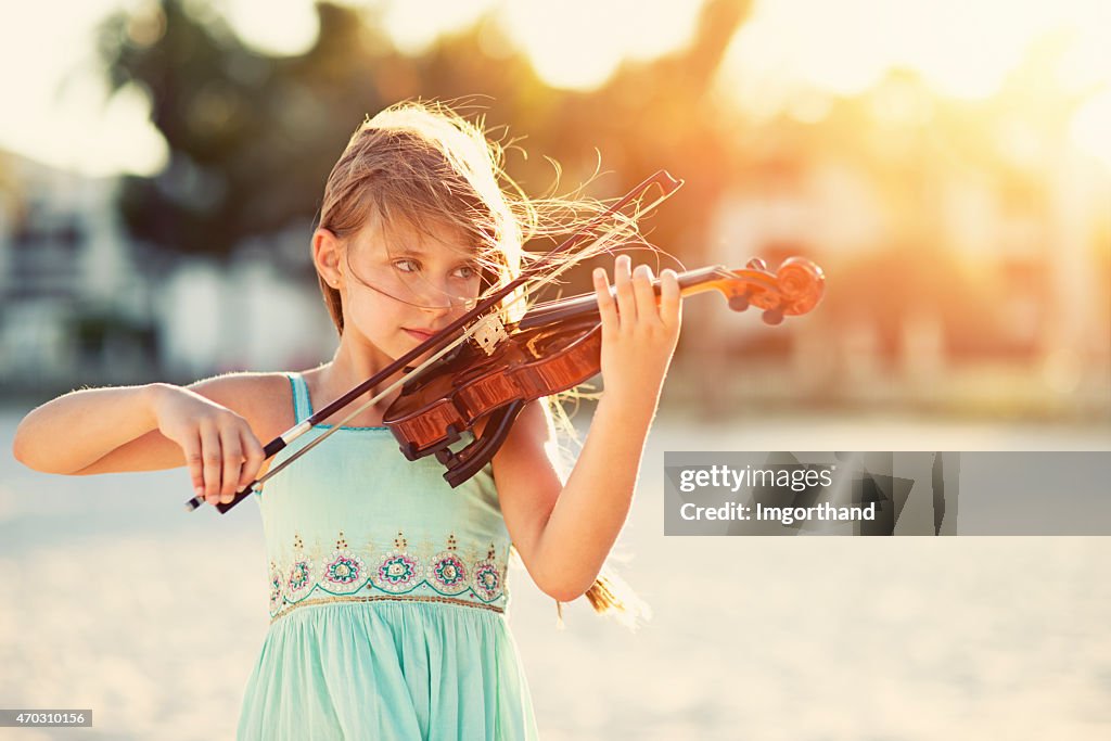 Music of the summer - girl playing violin on beach