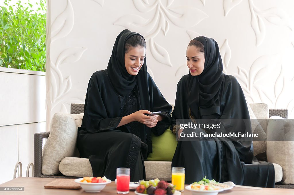Due donne degli Emirati in Abaya Texting sul cellulare a pranzo