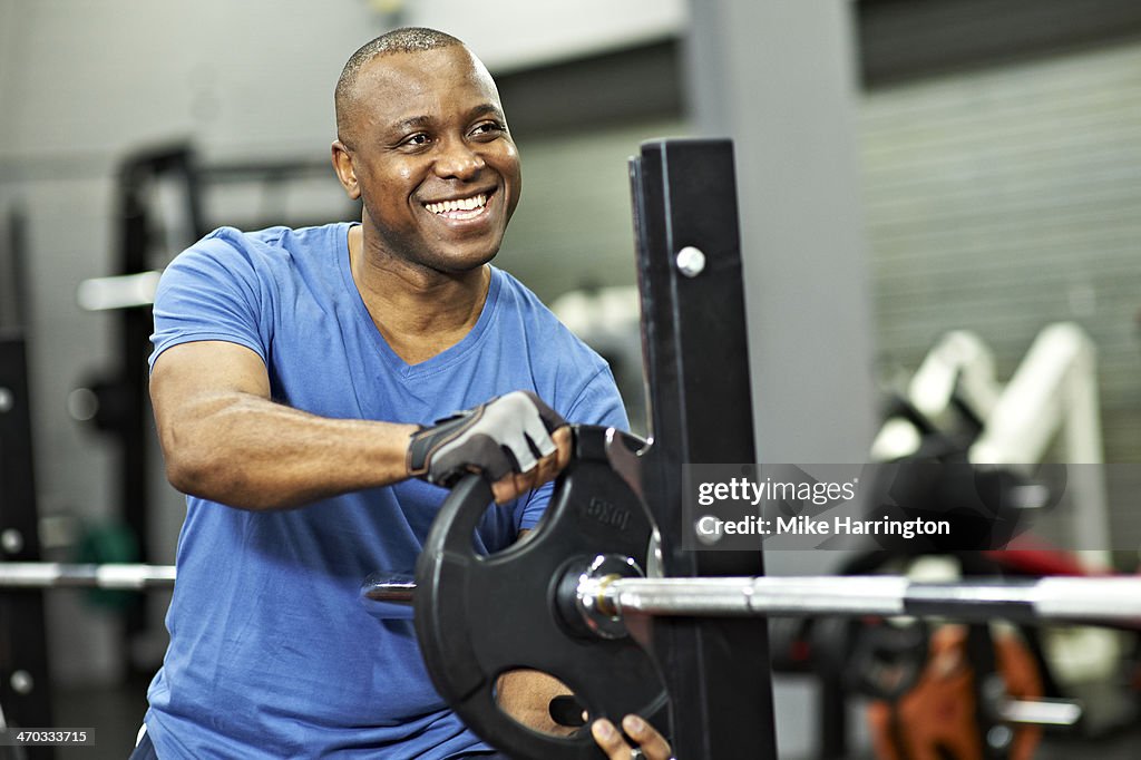 Black Male adding weight to gym equipment