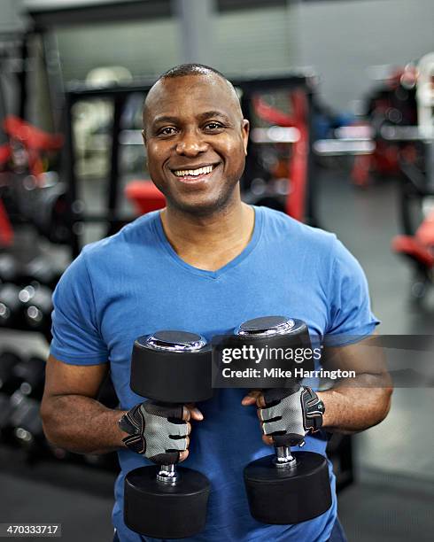 healthy black male holding weights in gym - differential stock pictures, royalty-free photos & images