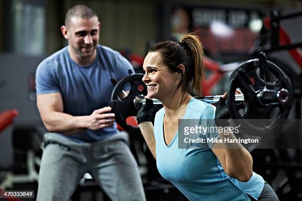 strong female lifting barbell in gym - krafttraining stock-fotos und bilder