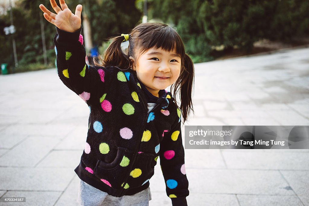 Toddler girl dancing joyfully in park