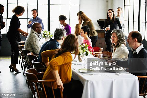 group of friends sitting down at banquet table - festmahl stock-fotos und bilder