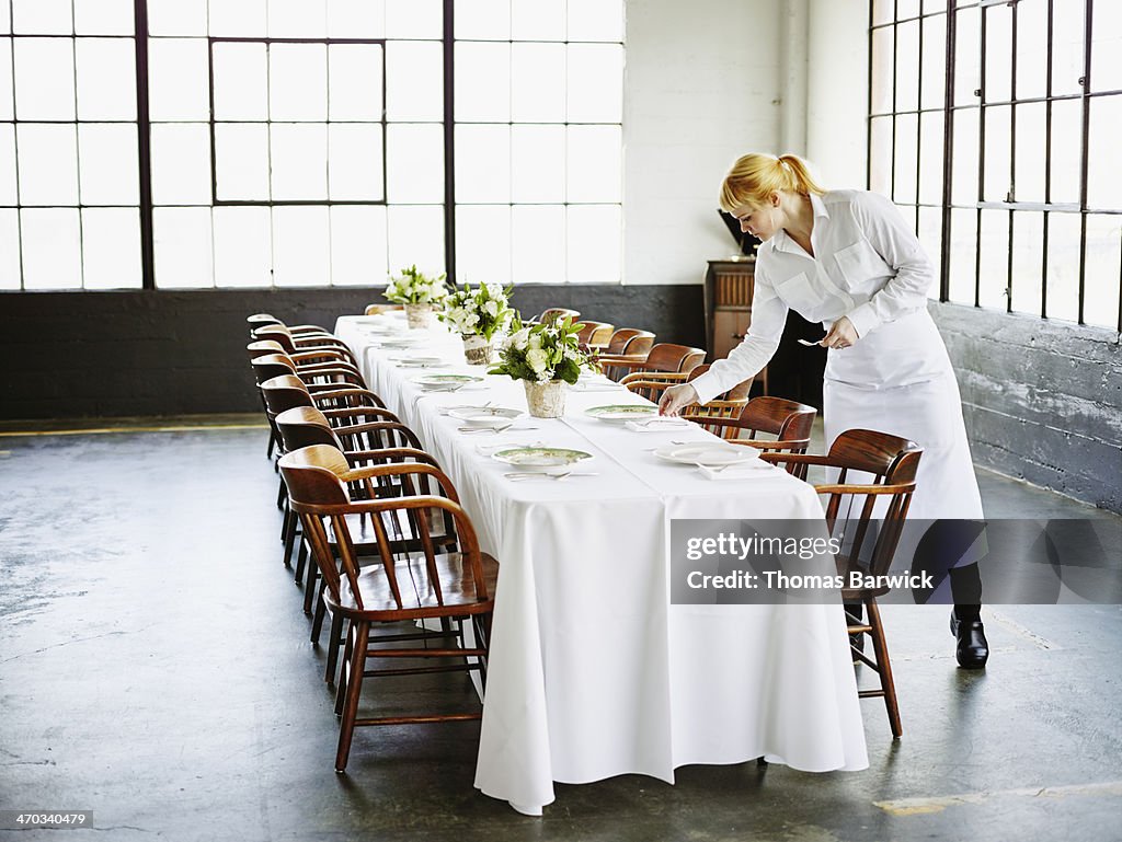 Waitress setting banquet table for dinner party