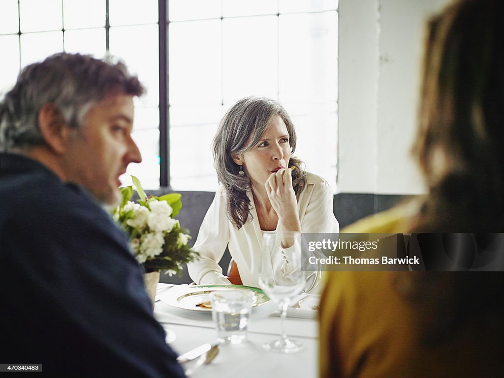 Woman sitting with friends at dinner party