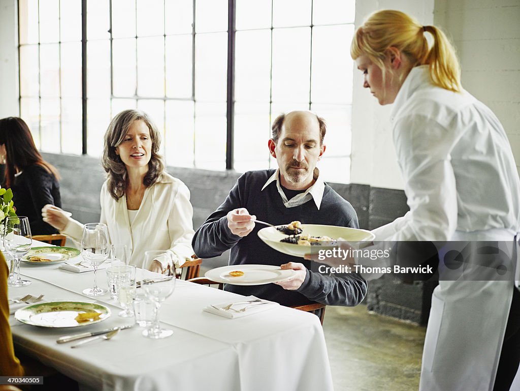 Man sitting with friends at party dishing up plate