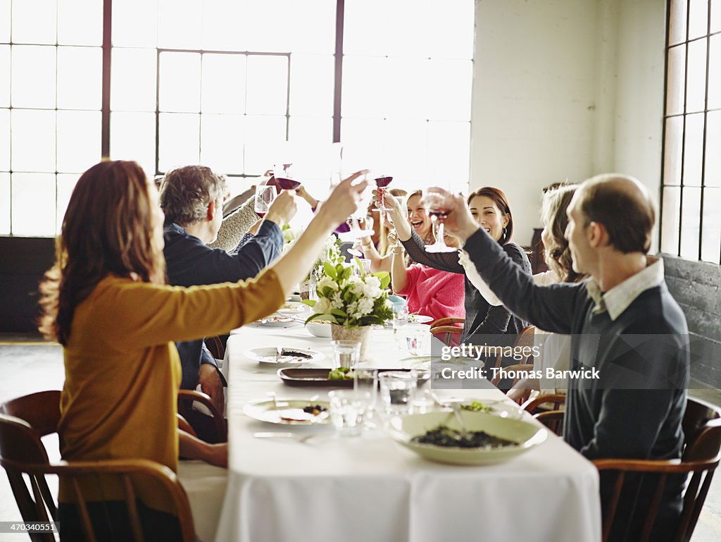 Group of friends toasting at dinner party in loft