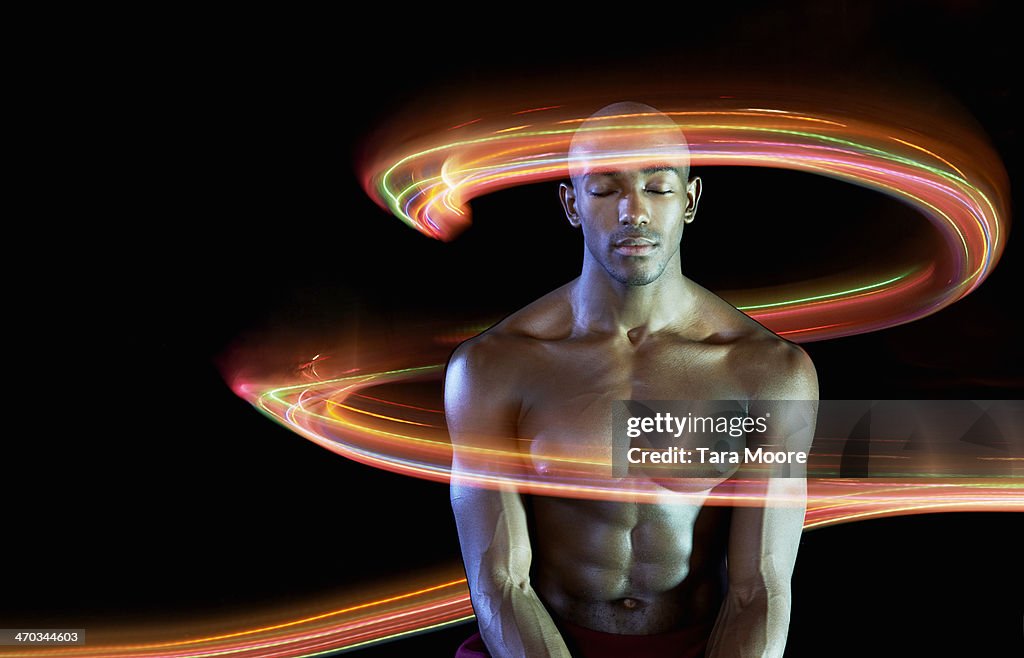 Strong man with eyes closed surrounded by light