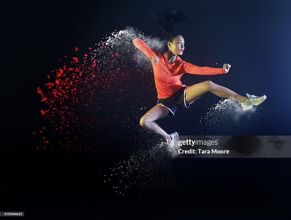 Sports woman jumping with coloured powder