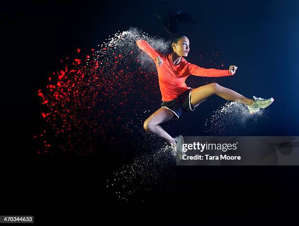 sports woman jumping with coloured powder - アスリート　黒背景 ストックフォトと画像