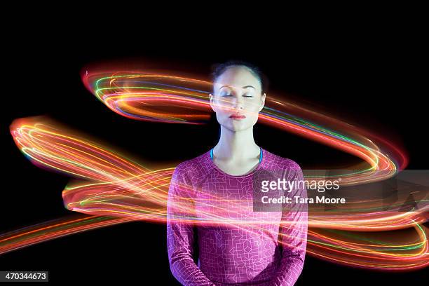 woman with eyes closed surrounded by light trails - circondare foto e immagini stock