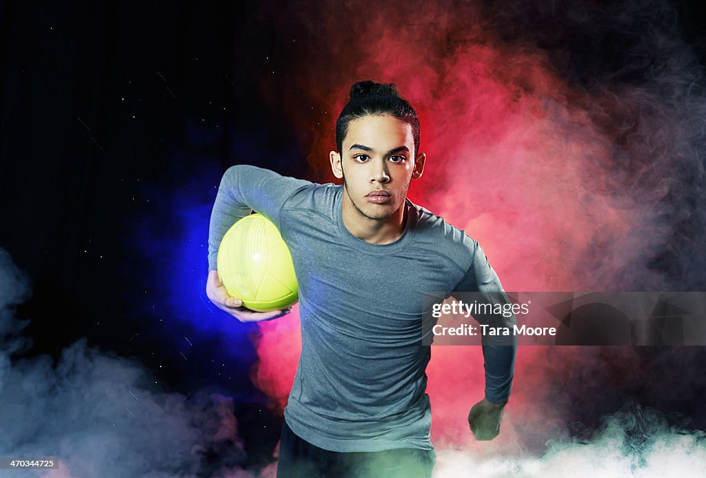 Man with football running through smoke