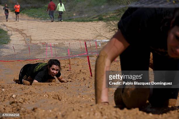 Competitors climb a muddy bank under a wire fence during the first Belik Race on April 19, 2015 in Cabanillas del Campo, in the region of...
