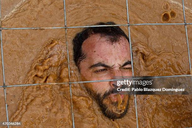 Competitor spits water as he passes under a fence through the water during the first Belik Race on April 19, 2015 in Cabanillas del Campo, in the...