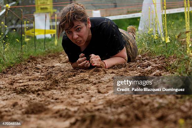 Competitor creeps along a muddy surface under electric wire during the first Belik Race on April 19, 2015 in Cabanillas del Campo, in the region of...