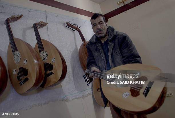 Hammad Atwa, a Palestinian man who makes lutes, known in Arabic as an "Oud" shows one of his handmade musical instruments at the Khan Younis refugee...