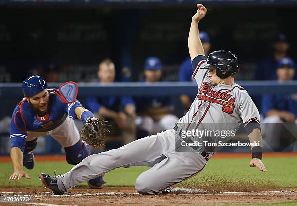 Chris Johnson of the Atlanta Braves slides across home plate safely to score a run on a sacrifice fly in the third inning during MLB game action as...