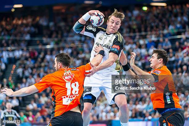 Filip Jicha of Kiel challenges Ferenc Ilyes and Alen Blazevic of Szeged during the VELUX EHF Champions League Quarter Final between THW Kiel and Pick...