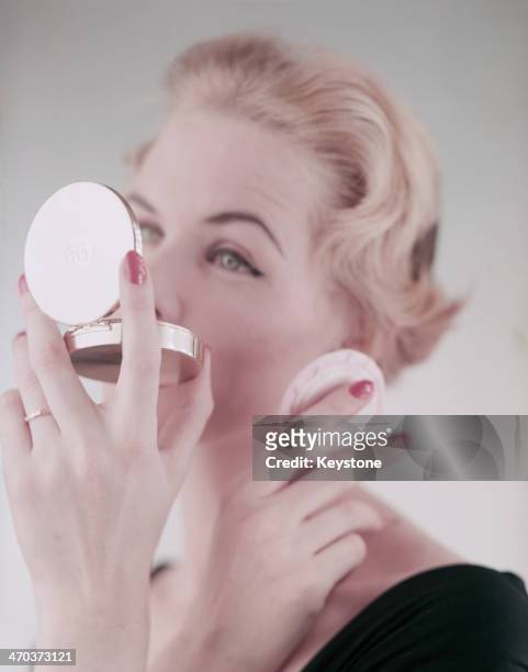 Woman using a powder compact, 1954.