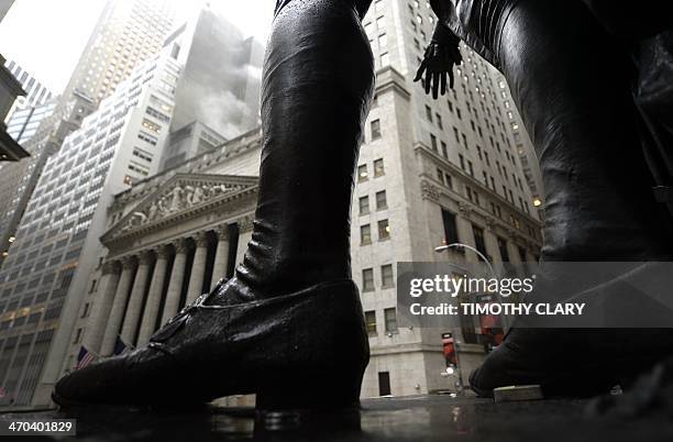 Rain falls with the New York Stock Exchange in the background as seen through the statue of George Washington at Federal Hall in Manhattan, on...