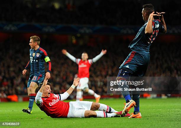 Jerome Boateng of Bayern Muenchen brings down Mesut Oezil of Arsenal in the area for a penalty during the UEFA Champions League Round of 16 first leg...