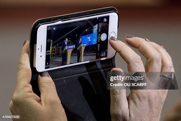 Woman takes a photograph on her mobile phone as British Prime Minister and leader of the Conservative Party, David Cameron and Conservative British...