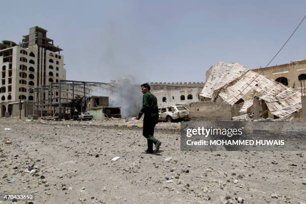 Yemeni man walks on along a damaged street following a raid by Saudi-led coalition warplanes on a missile depot on Fajj Attan hill, in the rebel-held...