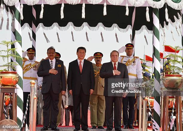 Handout picture released by the Press Information Department shows Chinese President Xi Jinping flanked by his Pakistani counterpart Mamnoon Hussain...
