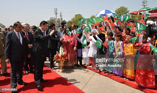 Handout picture released by the Press Information Department shows Chinese President Xi Jinping (waving to Pakistani children as his Pakistani...
