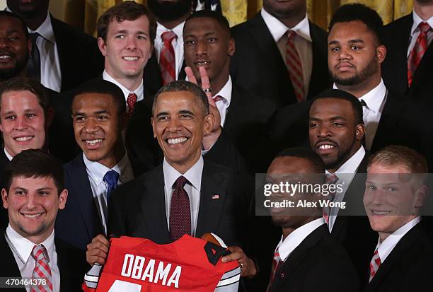 Michael Bennett, upper left, of the Ohio State University Buckyes football team holds up fingers behind the head of U.S. President Barack Obama...