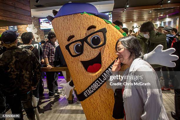 Woman poses for a photograph with the Tac bell mascot inside the new Taco Bell store during the official opening on April 21, 2015 in Tokyo, Japan....
