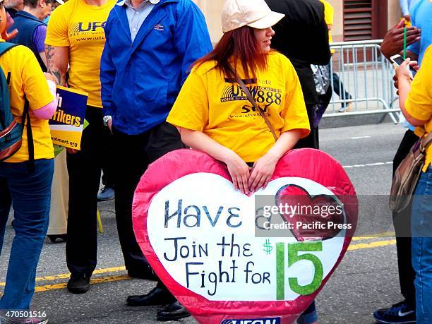 One marcher carries a heart shaped sign, asking people to have a heart and join the fight for $15. Thousands of people took part in the rally and...