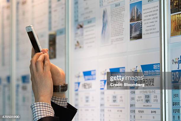 Jobseeker takes a photograph of job listings using his Apple Inc. IPhone 5 smartphone at a job fair in Goyang, South Korea, on Tuesday, April 21,...