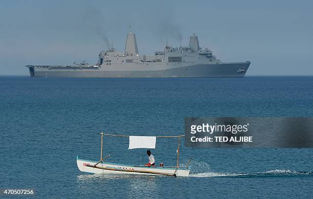 Filipino fisherman is seen past the US Navy amphibious transport dock ship USS Green Bay during an amphibious landing exercise on a beach at San...