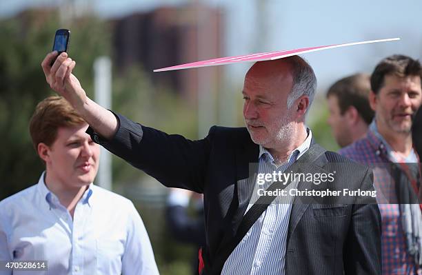 Labour party supporters use placards as sun shields as they await the departure of leader Ed Miliband after a speech on the Party's NHS rescue plan...