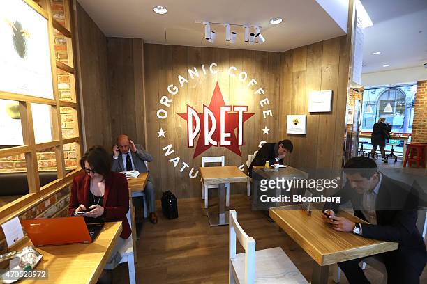 Customers use their mobile phones as they sit at tables inside a Pret A Manger sandwich store, operated by private equity firm Bridgepoint, in...