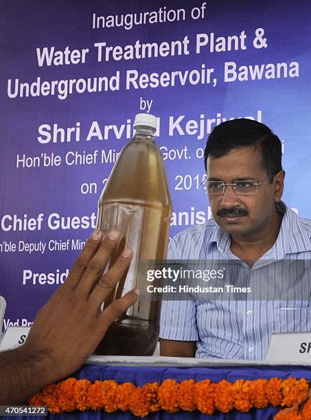 Residents of nearby area show a sample of contaminated and poor quality water to Delhi Chief Minister Arvind Kejriwal during the inauguration of the...