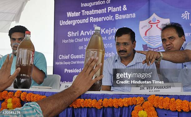 Residents of nearby area show a sample of contaminated and poor quality water to Delhi Chief Minister Arvind Kejriwal during the inauguration of the...