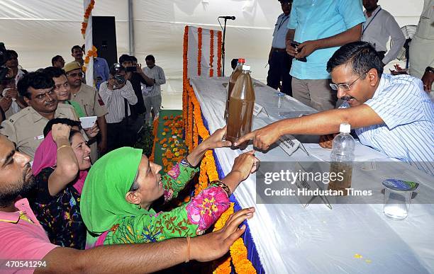 Residents of nearby area show a sample of contaminated and poor quality water to Delhi Chief Minister Arvind Kejriwal during the inauguration of the...